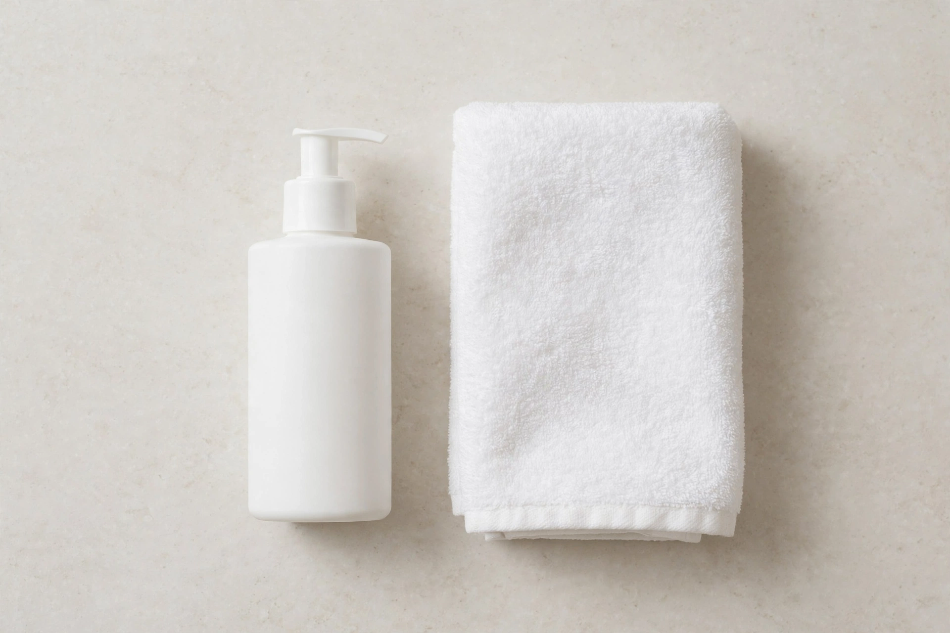 shower sex - Plain white pump bottle of silicone-based personal lubricant beside a folded towel on a bathroom counter